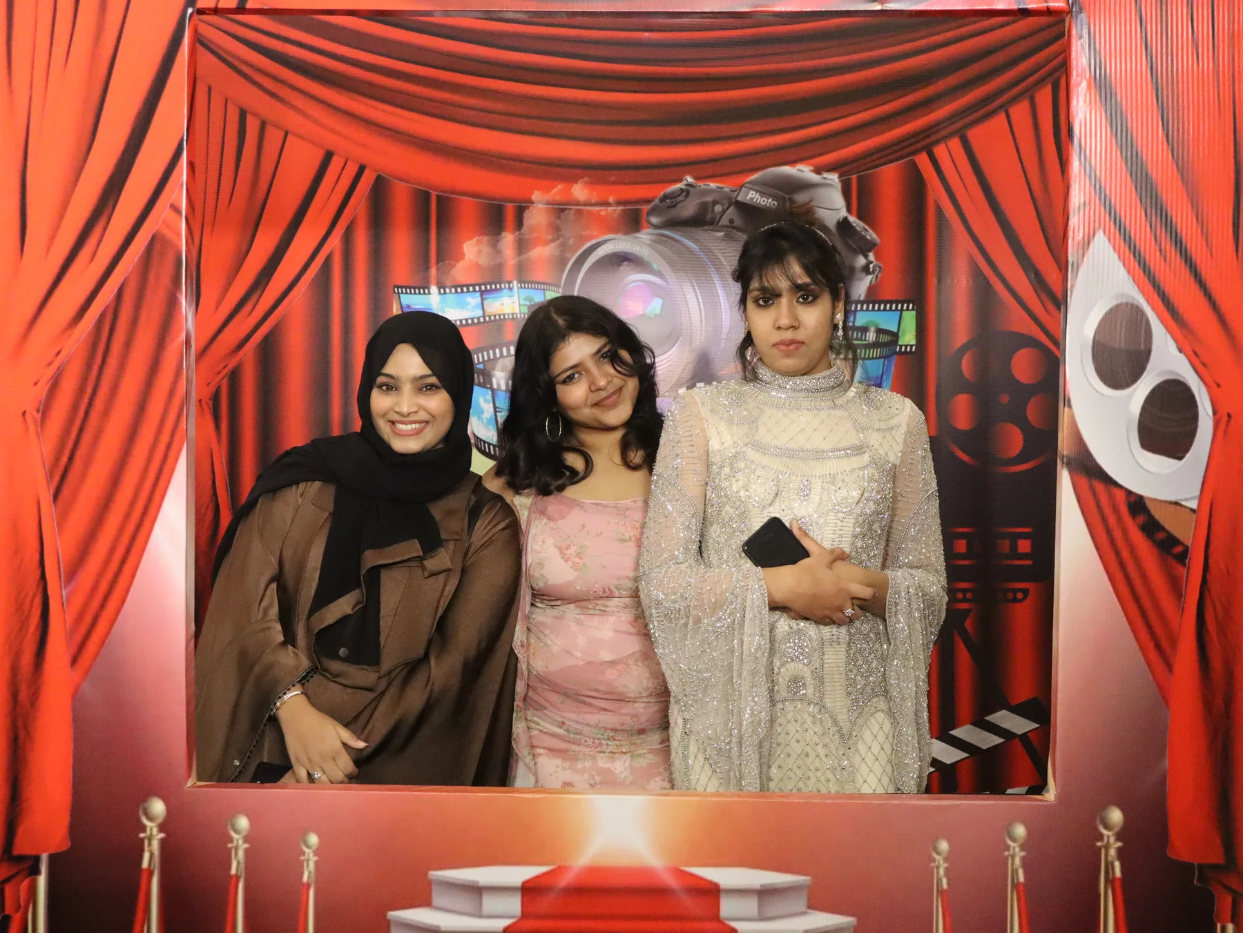 Three guests posing in an OctoSnap photo with a red cinema-themed template