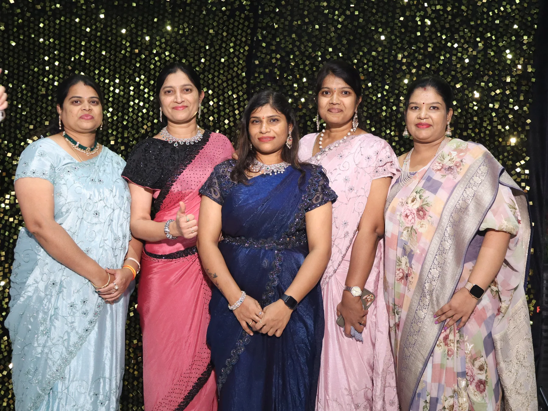 Five guests posing together at an OctoSnap photo booth against a sparkling backdrop