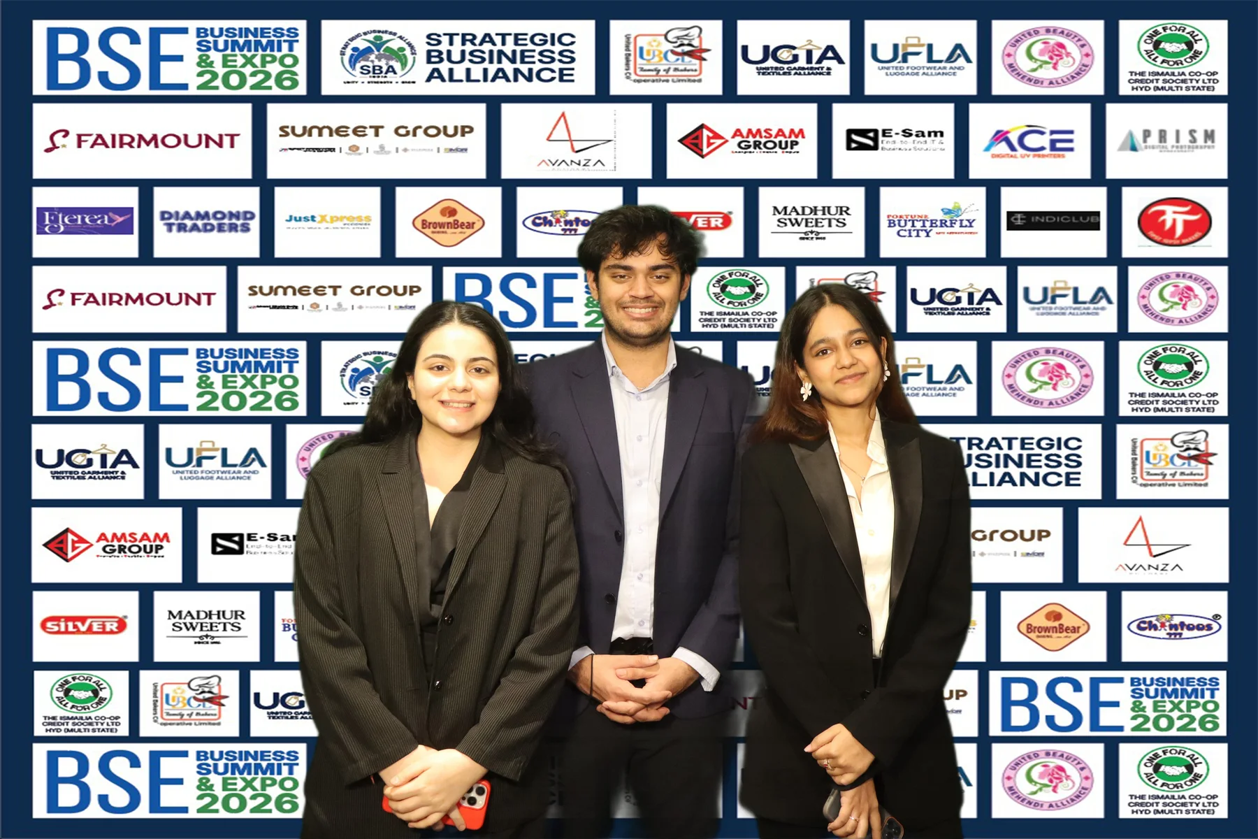 Three guests posing in front of a Business Summit and Expo event backdrop